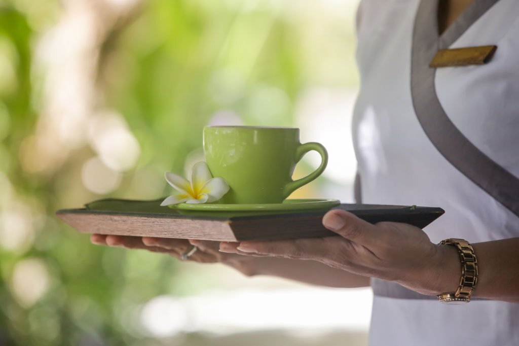 Close up image of a waiter holding a tray with a cup of tea of coffee Close up image of a waiter holding a tray with a cup of tea of coffee